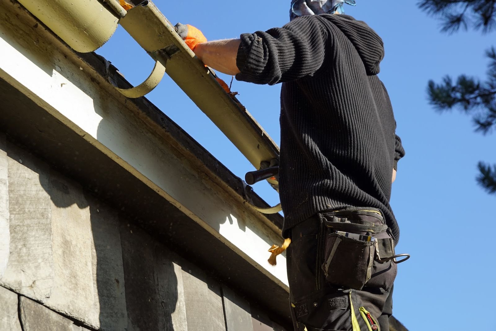 Technician clearing leaves from a gutter by hand