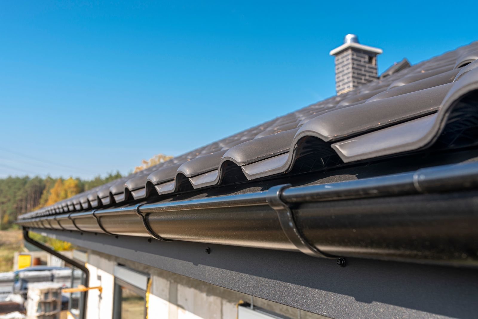 Clean gutter running along a tiled roofline against a blue sky