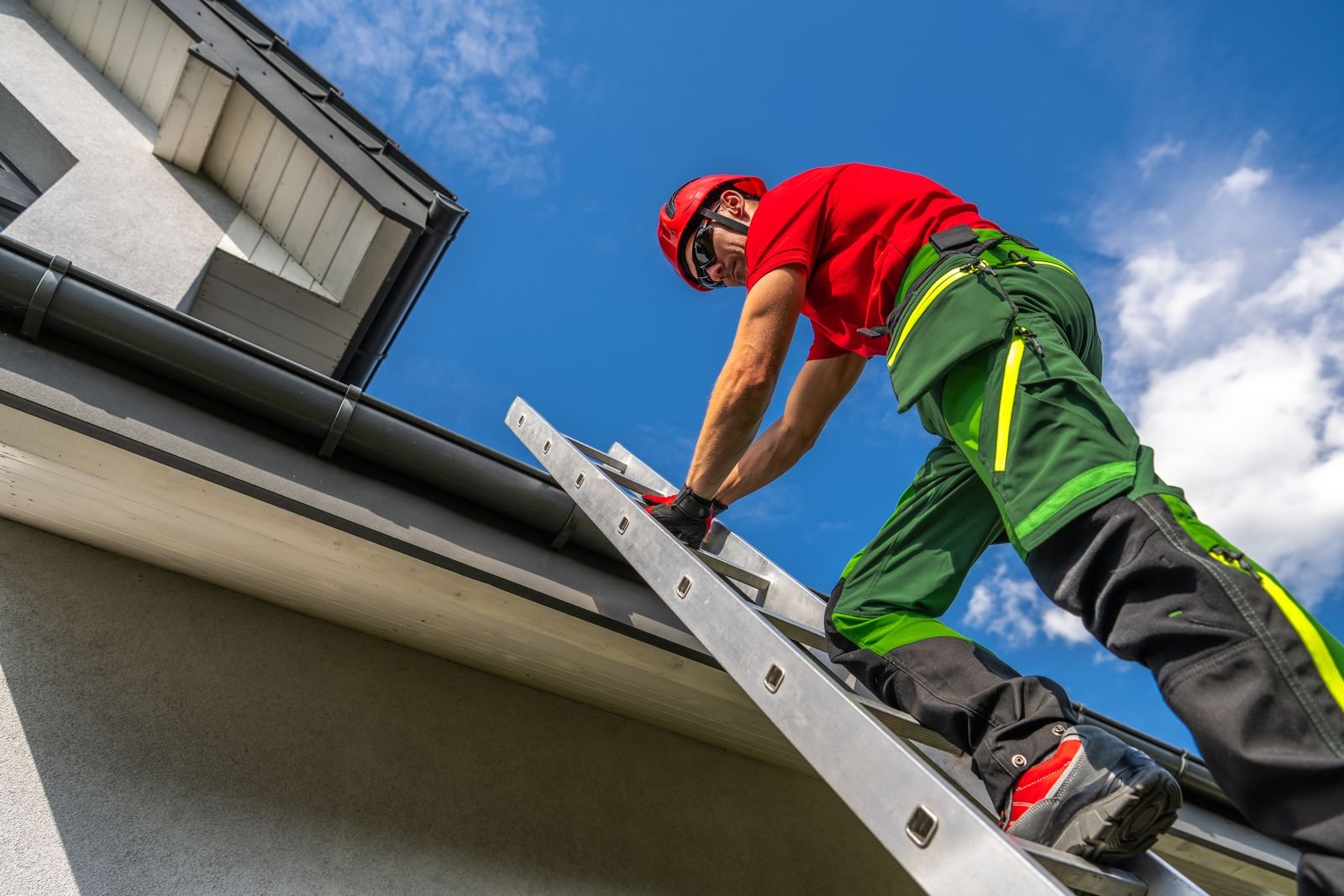Worker on a ladder inspecting a residential gutter
